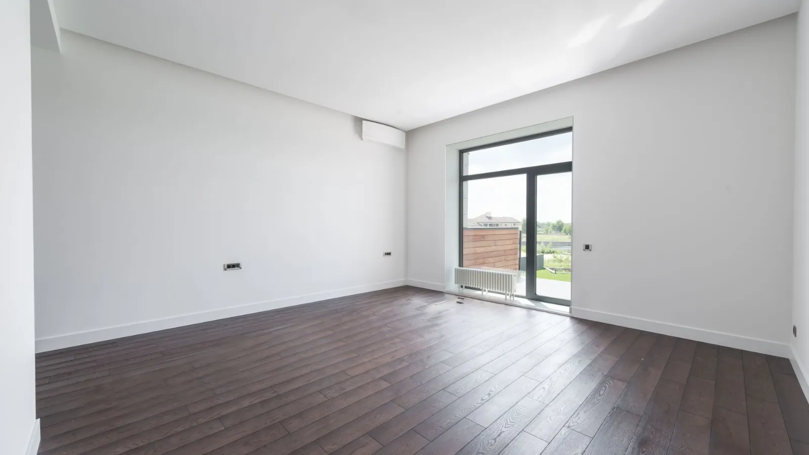 Yeni teslim edilmiş bir dairede koyu tonlu parke zemin ve balkon kapısı